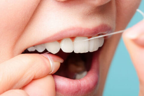 young woman flossing her teeth