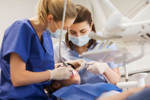 two dentists doing dental treatment of a child